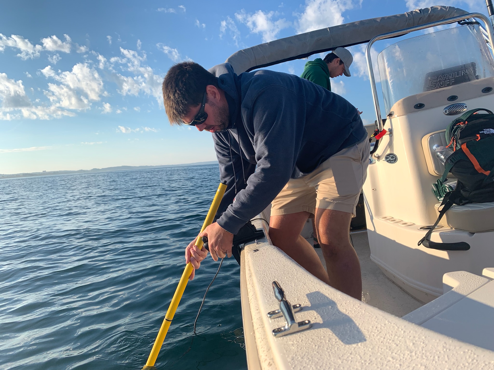 MSU Assistant Professor Ethan Theuerkauf leaning over the side of a boat