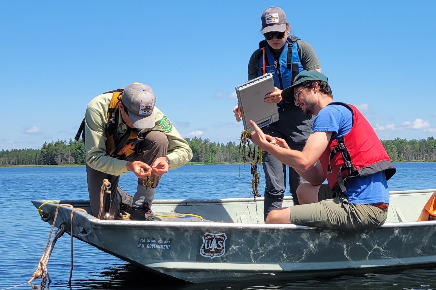 Three MSU Extension members in a boat taking lake samples