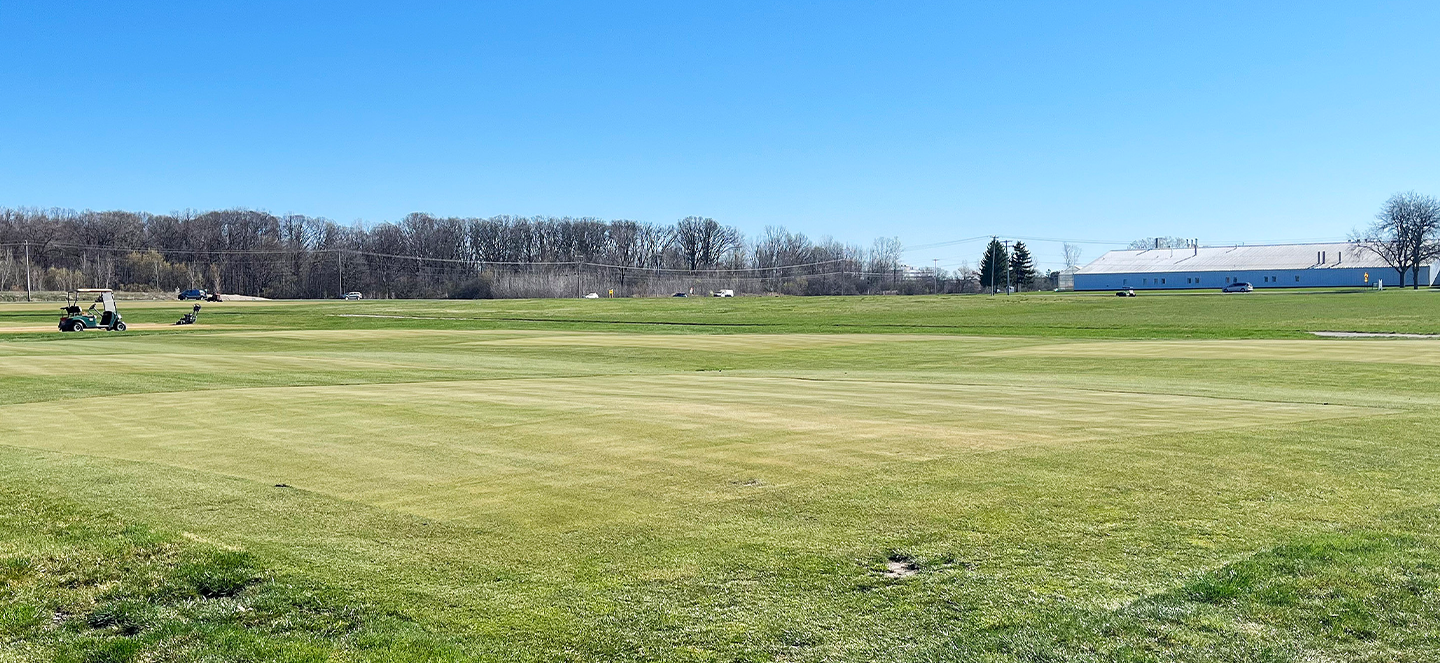 A putting green with an irrigator in the background