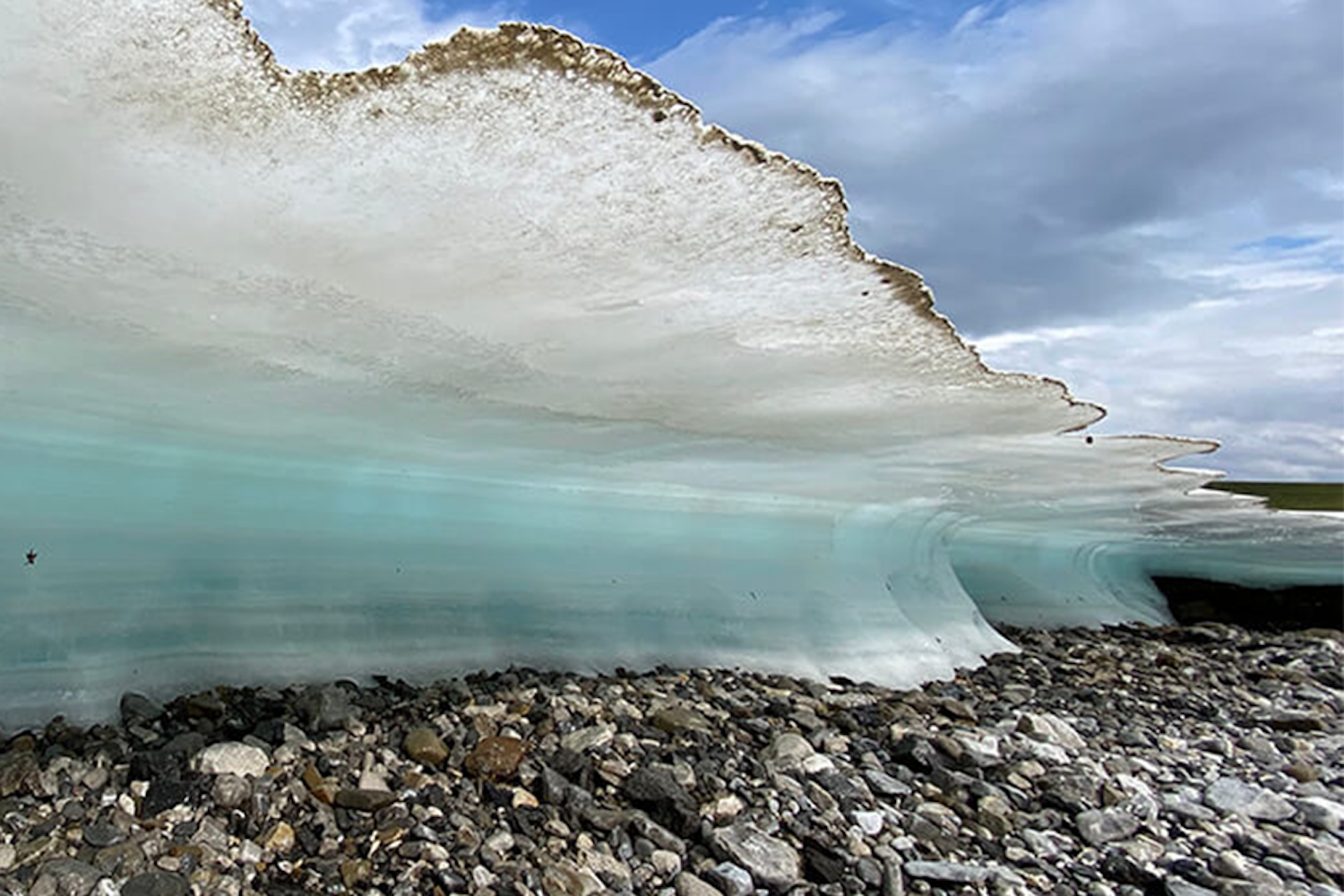 A sheet of ice frozen over rocks on a shoreline