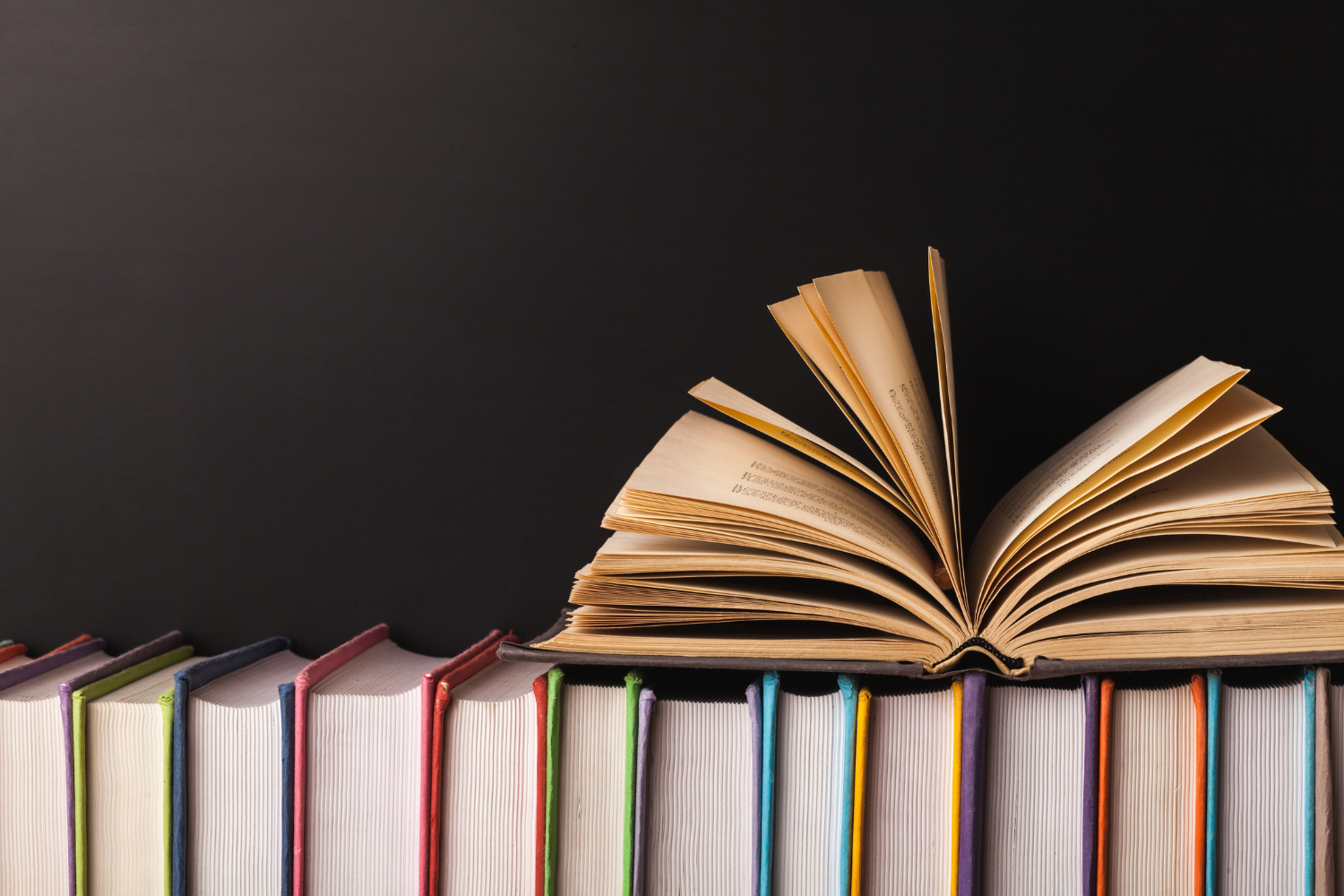 One book open on top of a stack of books.