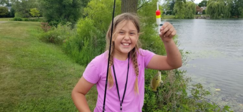 Little girl standing in front of a lake.