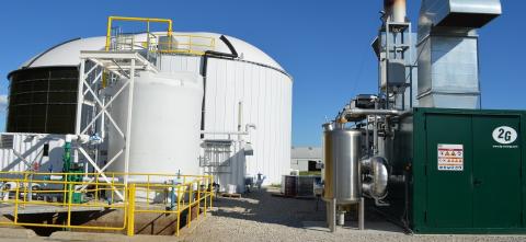 Industrial facility with large tanks, pipes, and metal structures under a clear sky.