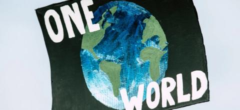 A painted sign shows the Earth with the words “One World.”